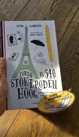 Kinderboek in een linkerhand over Parijs met hout op de achtergrond