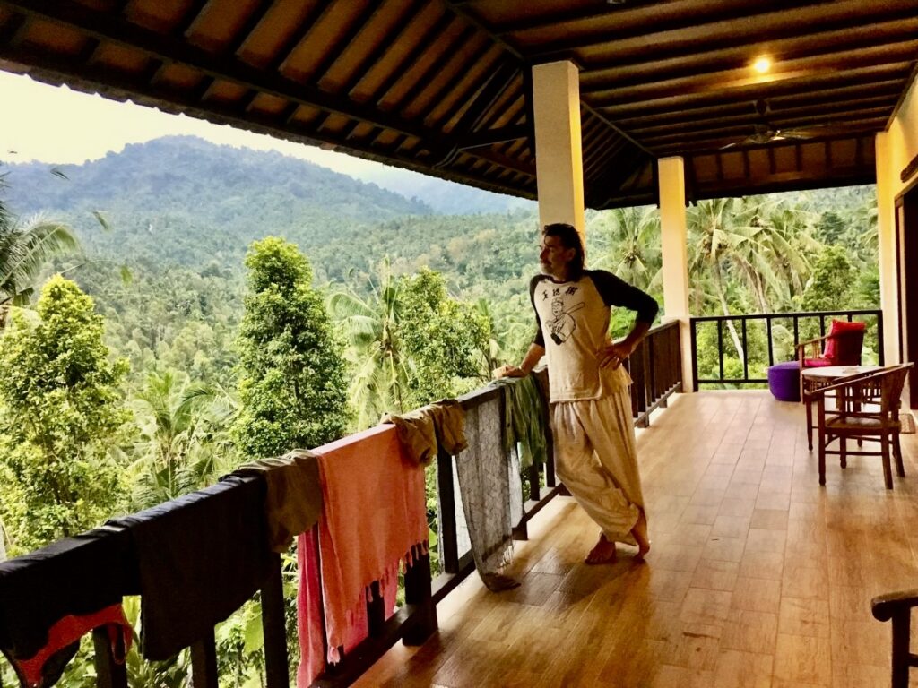 Man staat op een veranda en kijkt uit over de jungle