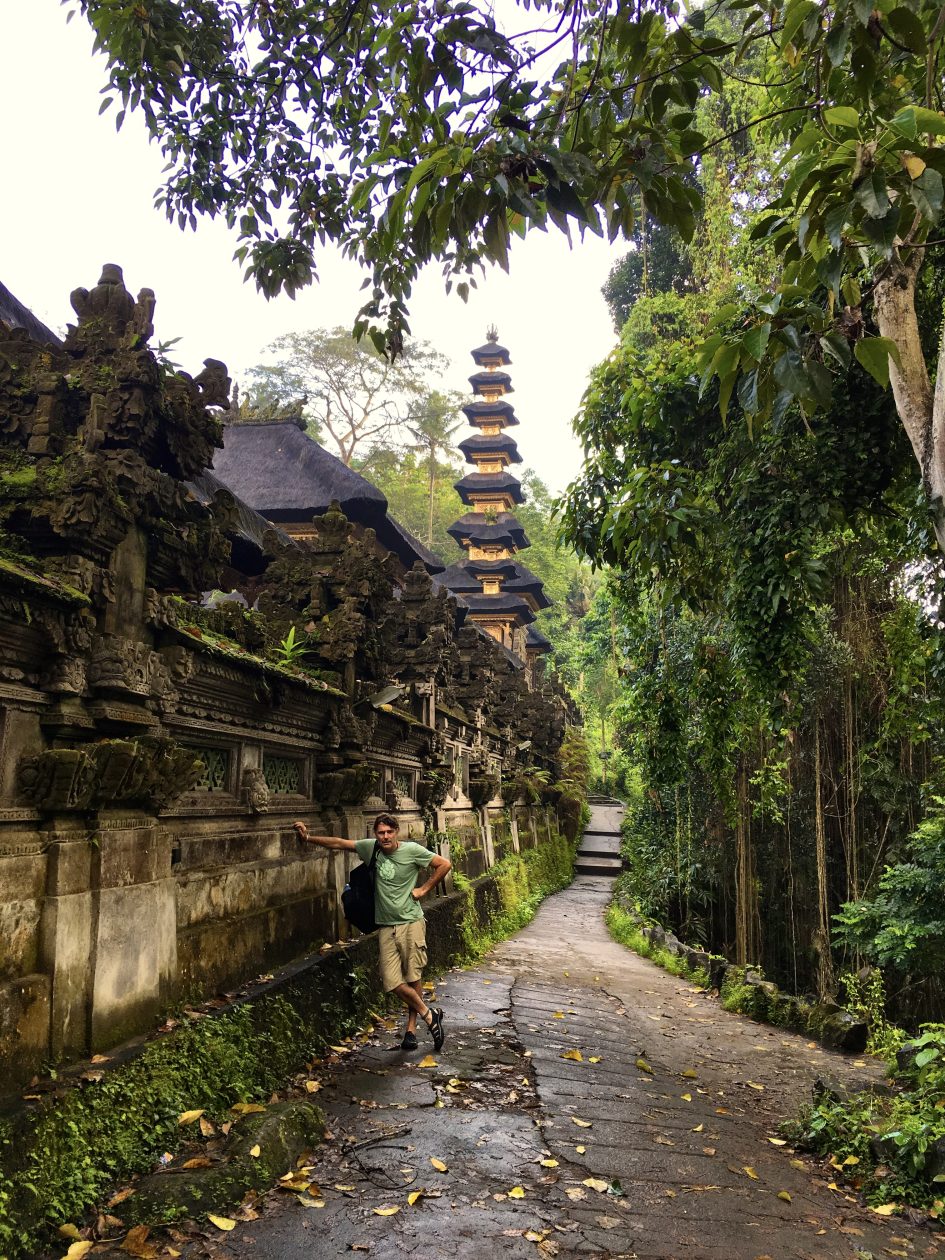 man naast een tempel in een tropische omgeving