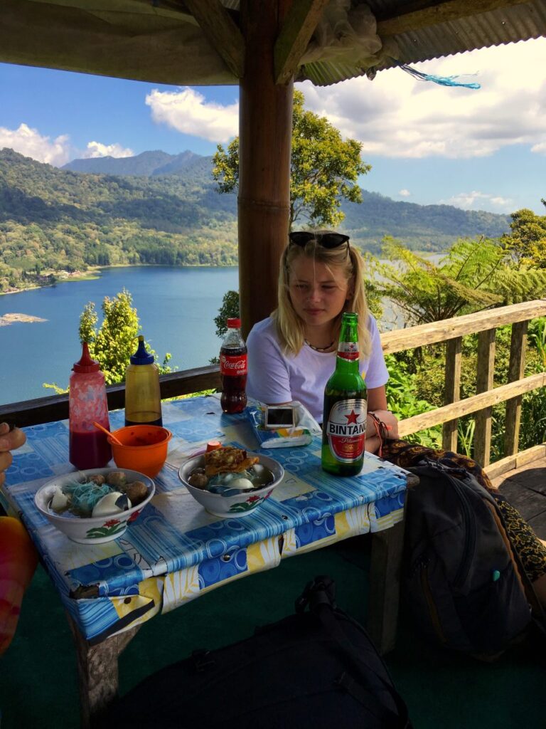 terras met afdak met een meisje eronder met op de achtergrond een meer omzoomd door bergen