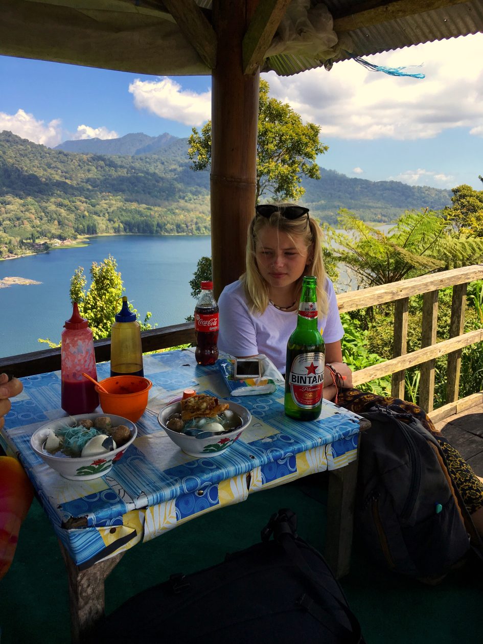 terras met afdak met een meisje eronder met op de achtergrond een meer omzoomd door bergen