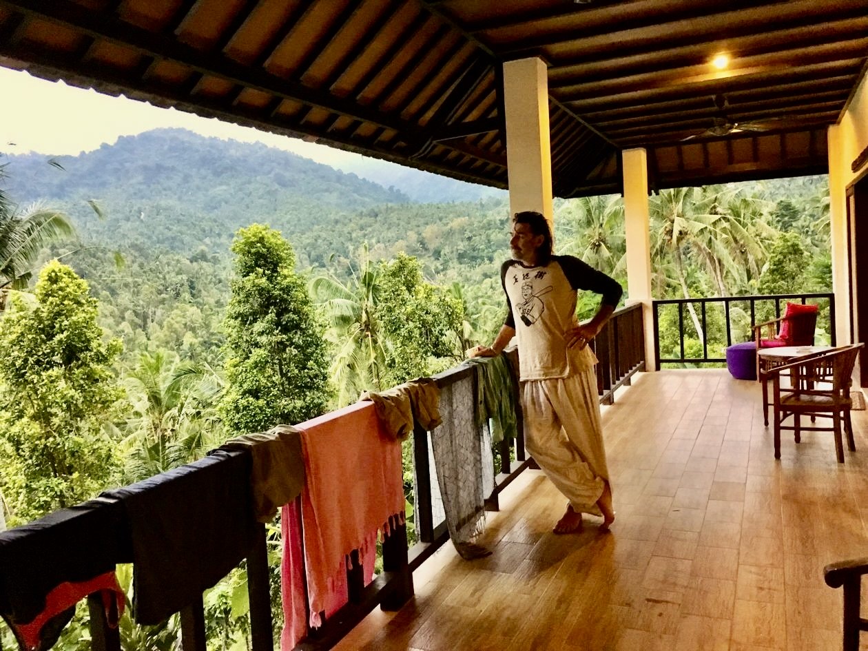 Man staat op een veranda en kijkt uit over de jungle