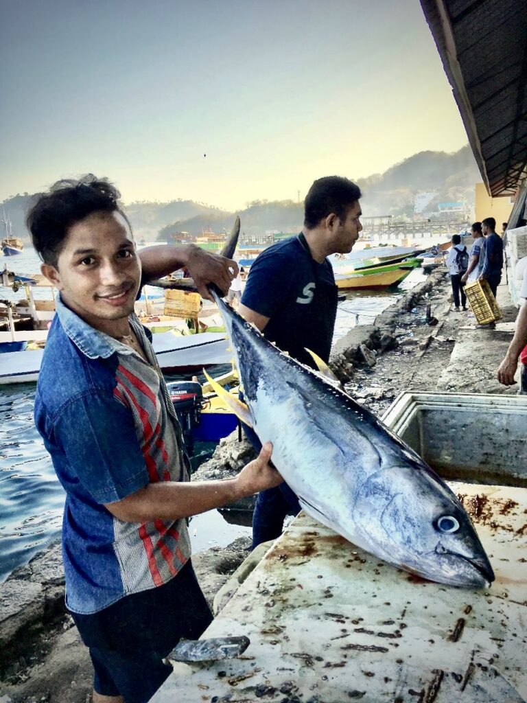 Jonge man op de kade met een Tonijn in zijn hand