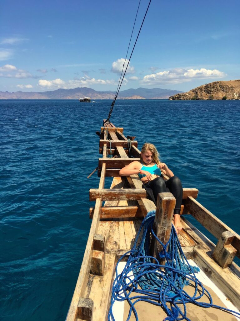 Meisje zit in de punt van een traditionle houten boot uit Indonesie op zee