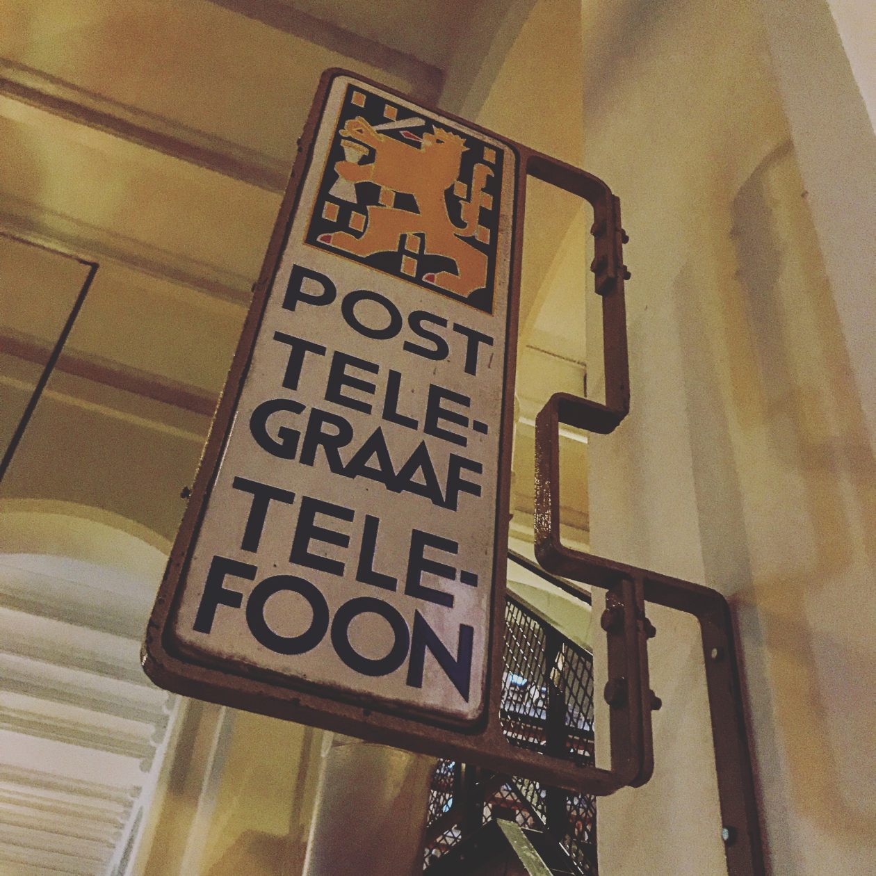 Oud emaile bord van de PTT hangend in een deftige gang