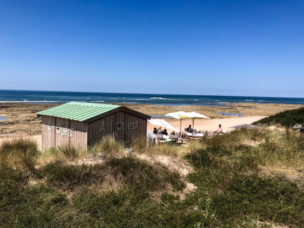 Strandtentje met op de voorgrond de duinen en daarachter de zee