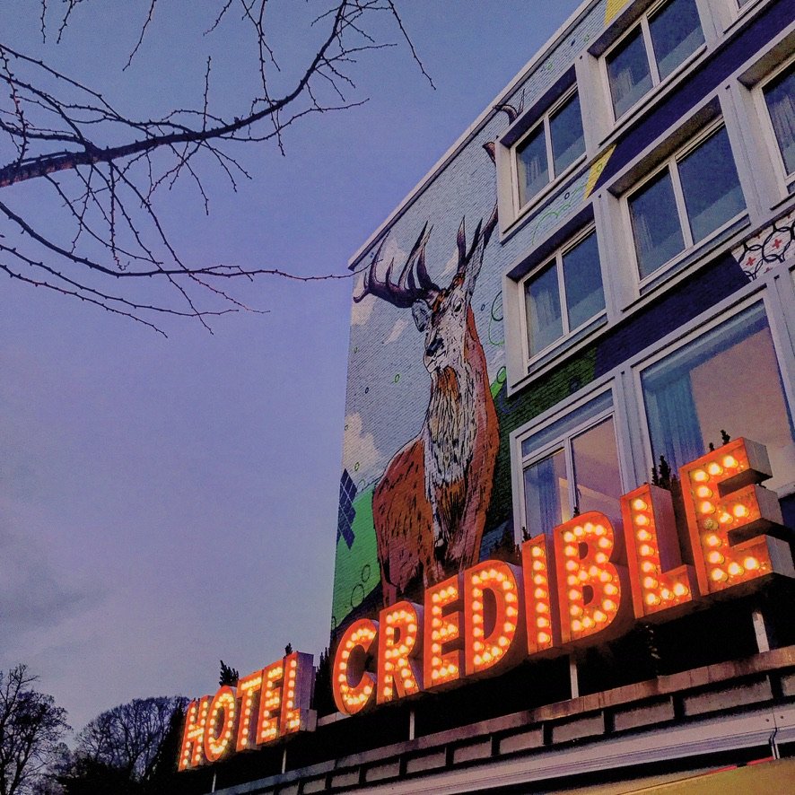 Licht reclame op een pand in het duister met de tekst HOTEL CREDIBLE