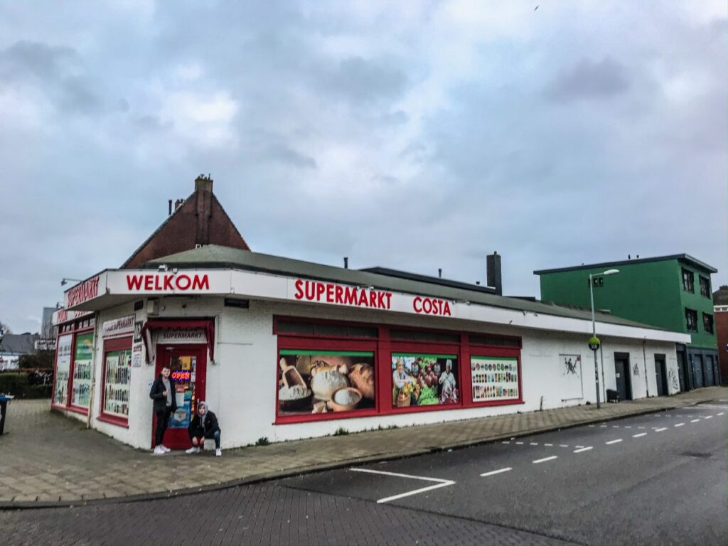 we zien een wit gebouw in amsterdam waar een poolse supermarkt in huist