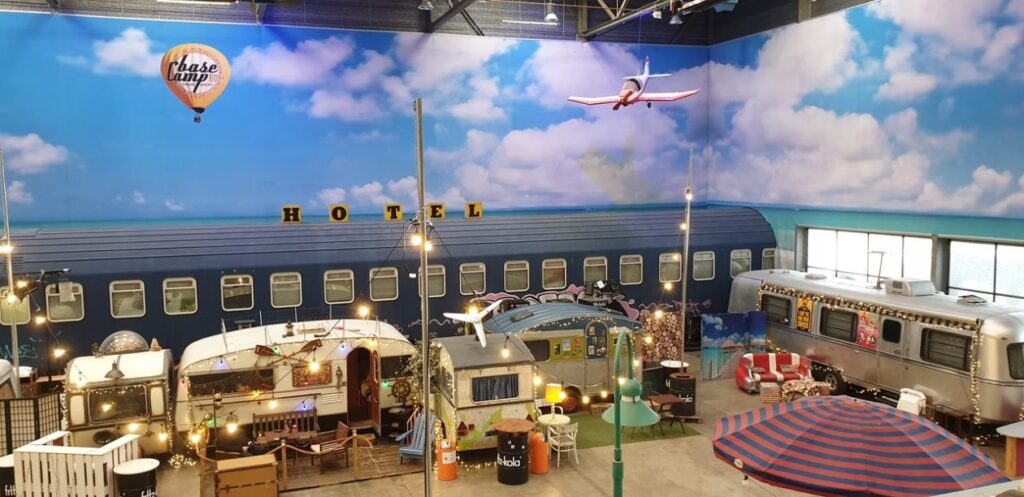 een indoor kamping met geschilderde lucht boven de Caravans