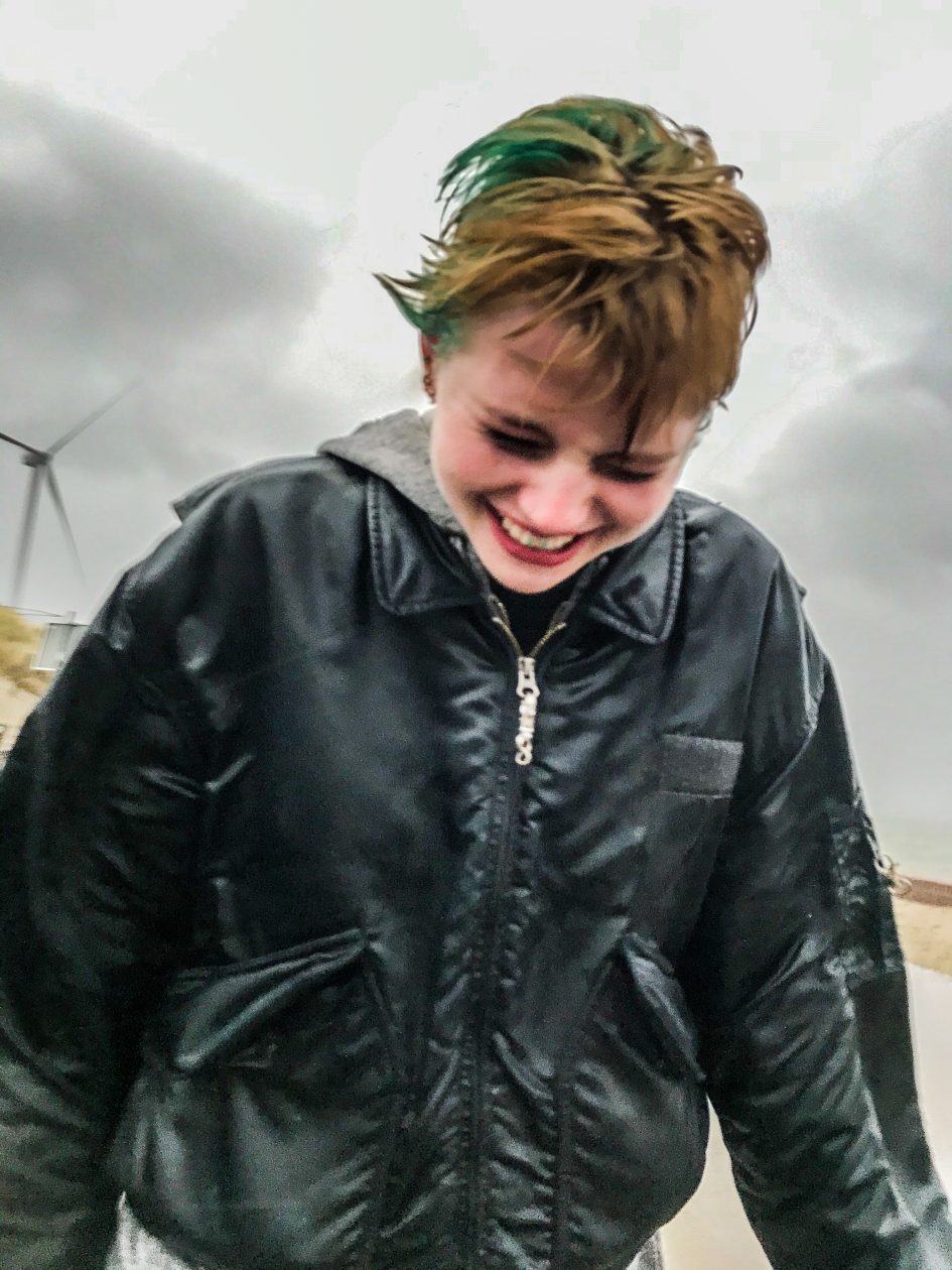 Meisje met zwarte jas loopt met gebogen hoofd tegen de regen in