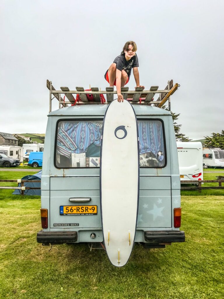 meisje boven op een camper laat haar surfboard zakken