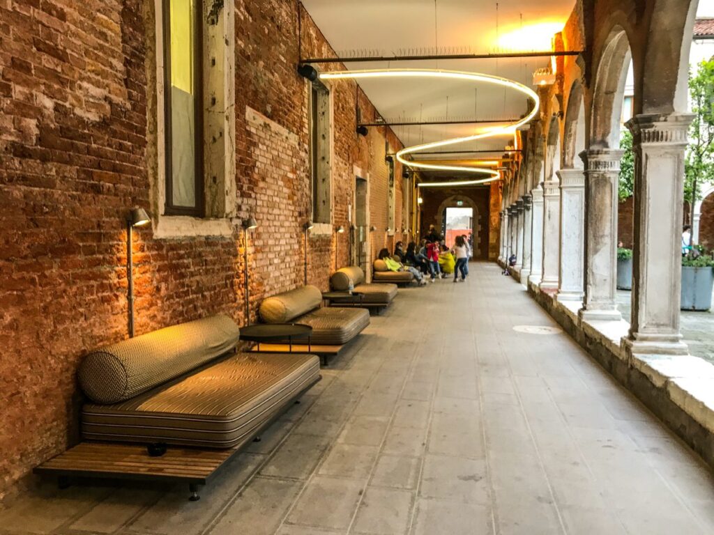 Oud klooster verbouw tot hostel; met links banken en een lamp als kunstobject aan het plafond