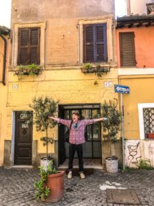 Man met armen wijd voor een italiaans geel huisje