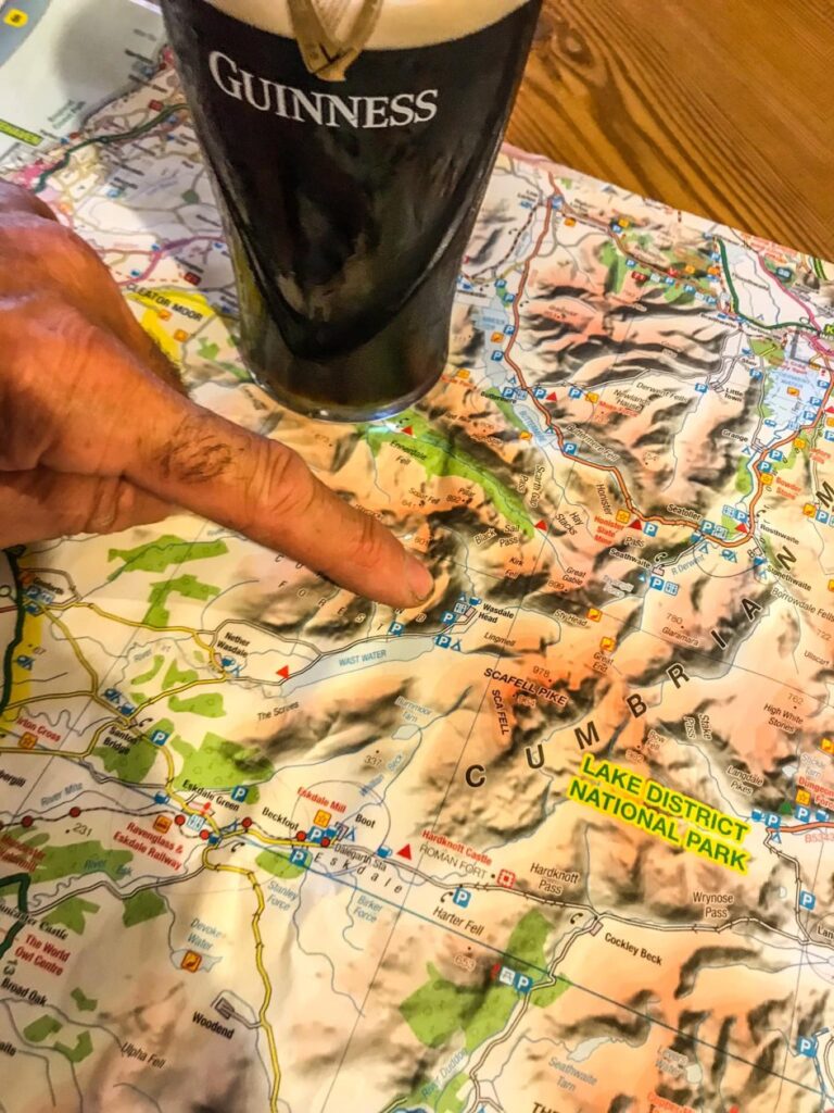 Vinger die wijst op een landkaart met daarnaast een glas bier