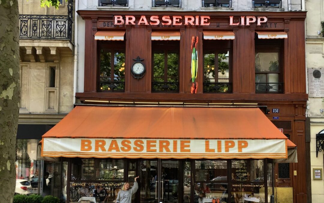 Exterieur van Brasserie Lipp in Parijs met meisje die wijs naar de zonnewering