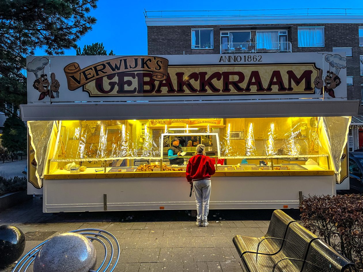 oud hollandse oliebollen kraam op een plein met een vrouw ervoor