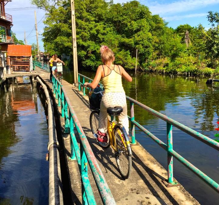 Meisje op een fiets op een smal bruggetje in Bangkok
