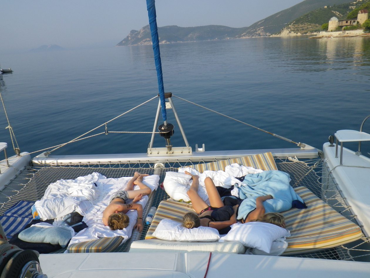 punt van een catamaran met slapen kinderen in het net tussen de twee boegen