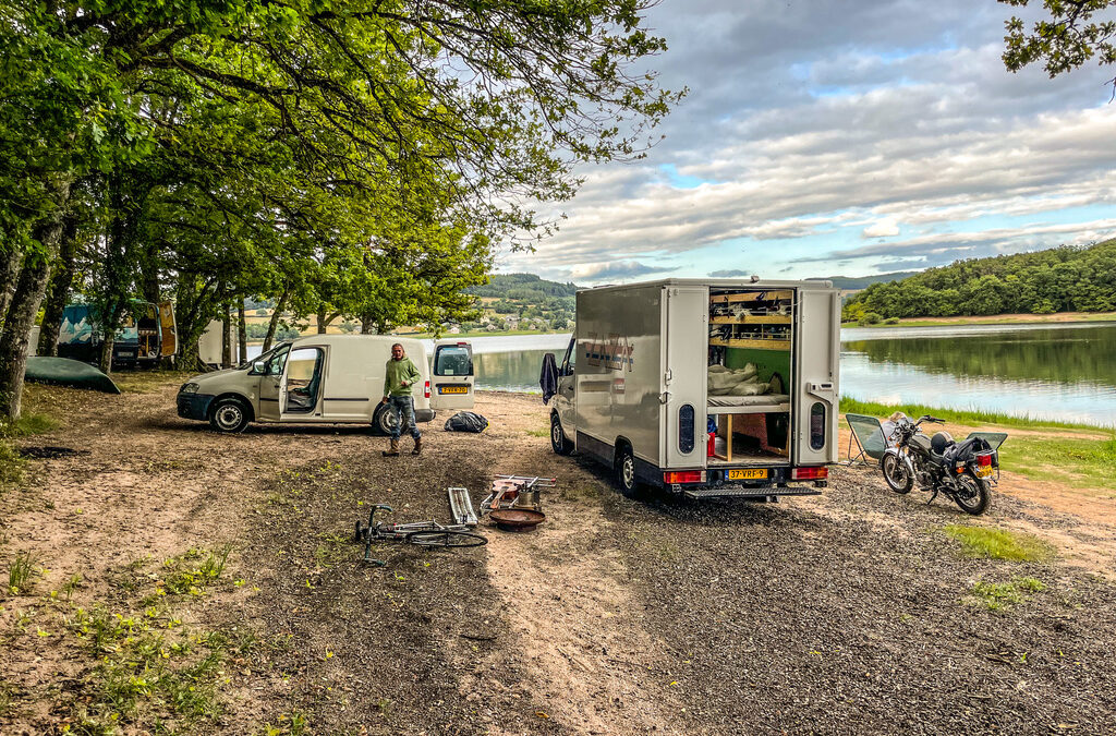 camper aan meer met links bomenrij