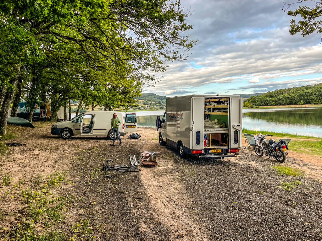 camper aan meer met links bomenrij