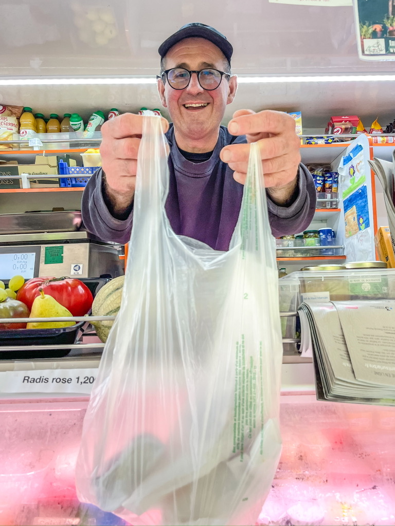 man reikt plastic zak uit srv wagen