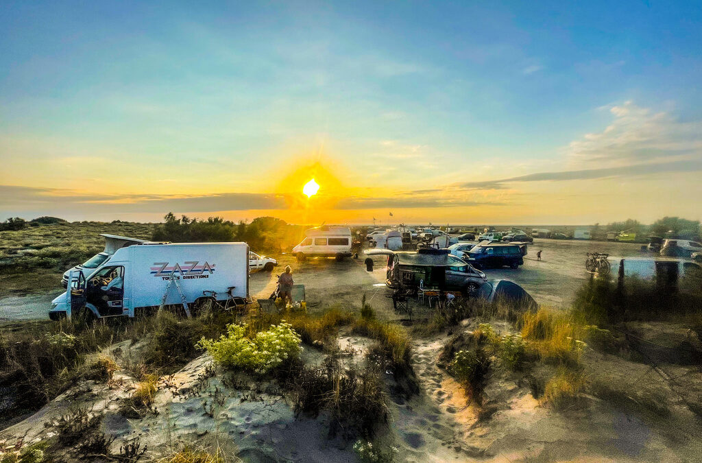 duinen met campers en een ondergaande zon