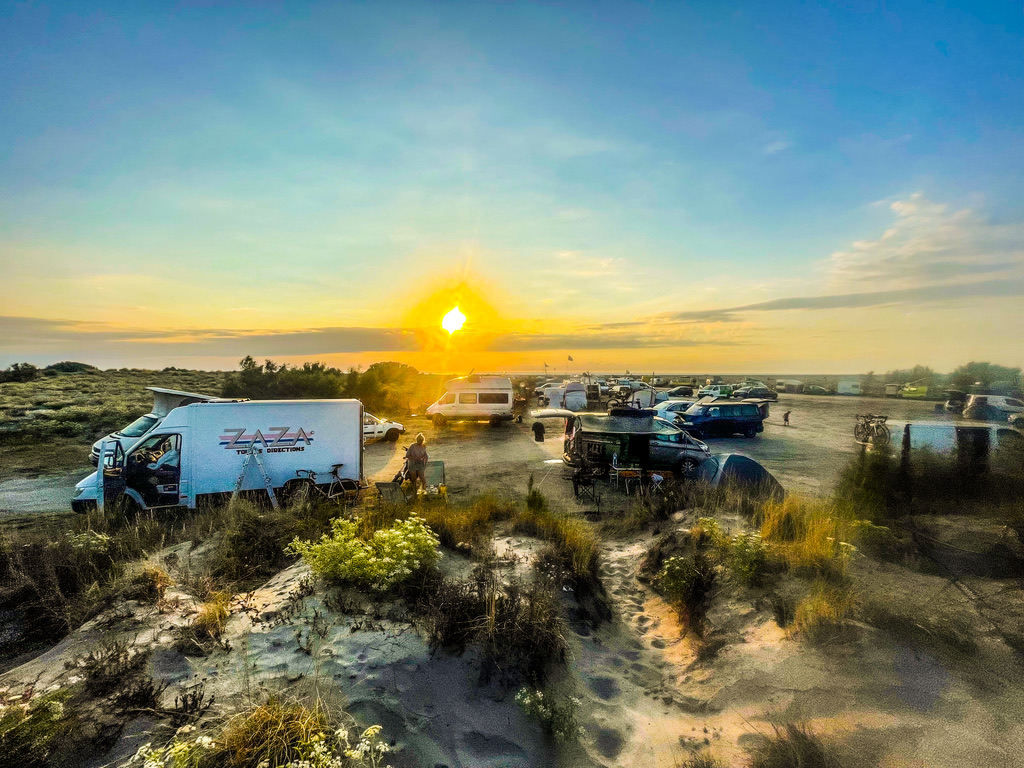 duinen met campers en een ondergaande zon