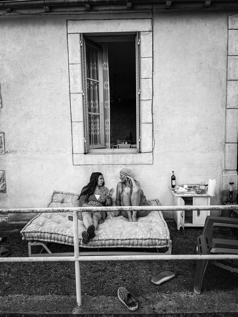 twee vrouwen buiten op een bed tegen een huis aan