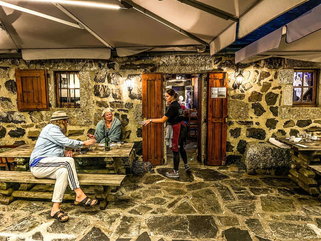 Terras met flagstones op de vloer en twee gasten aan houten tafels