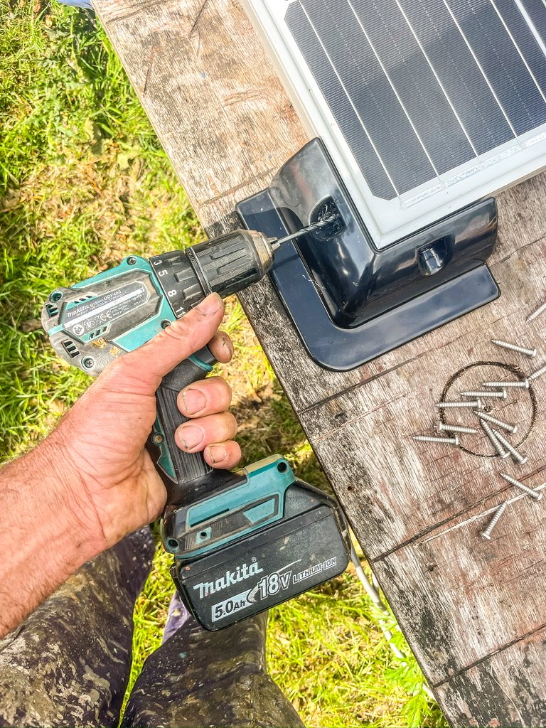 Hand met boortol die een plastic pootje bevestigd aan een zonnepaneel