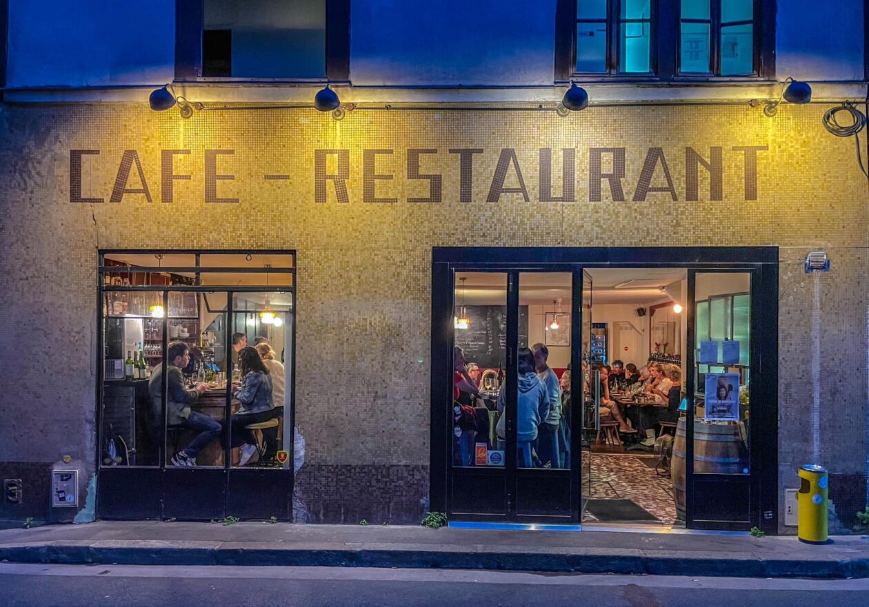 Exterieur van een restaurant in een straat uitgelicht met twee lampen