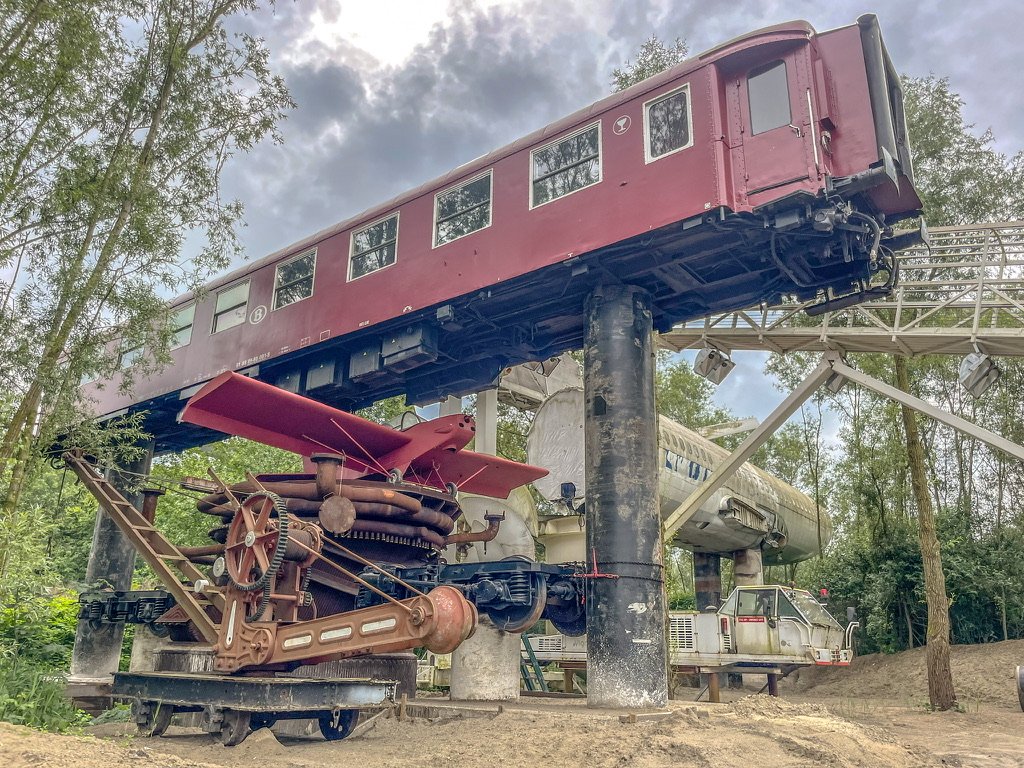 een trein in de bomen eronder een vliegtuig , we zijn aangeland bij het museum van onbedoelde kunst