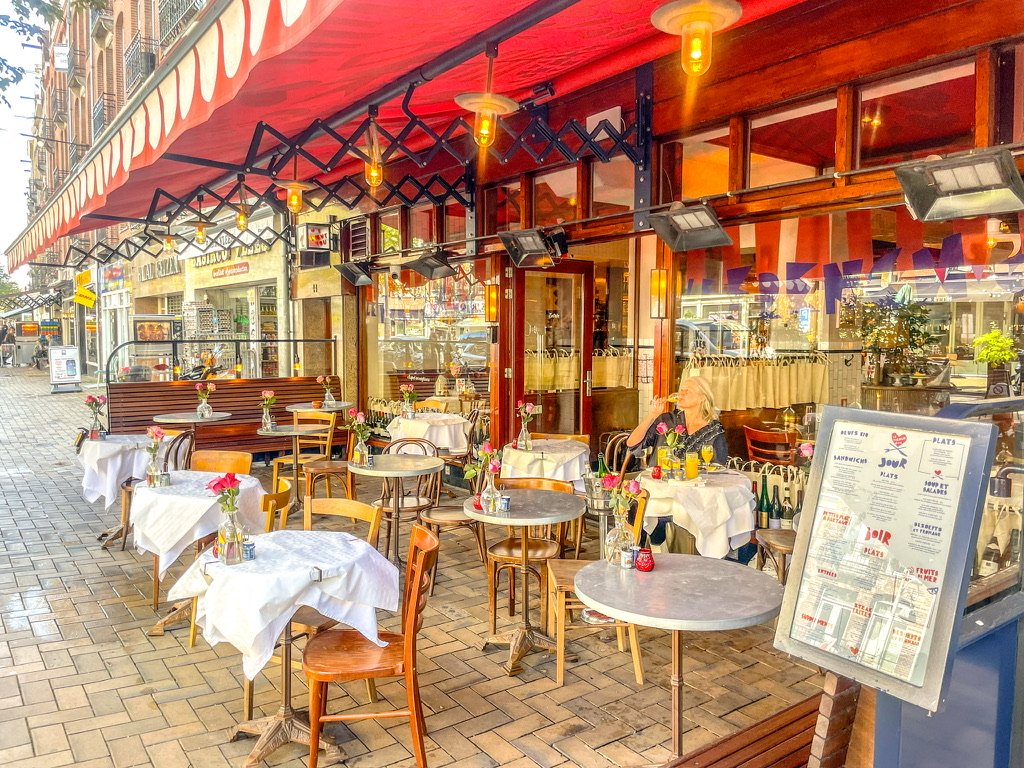 een bistro met een rode luifel en het terras eronder