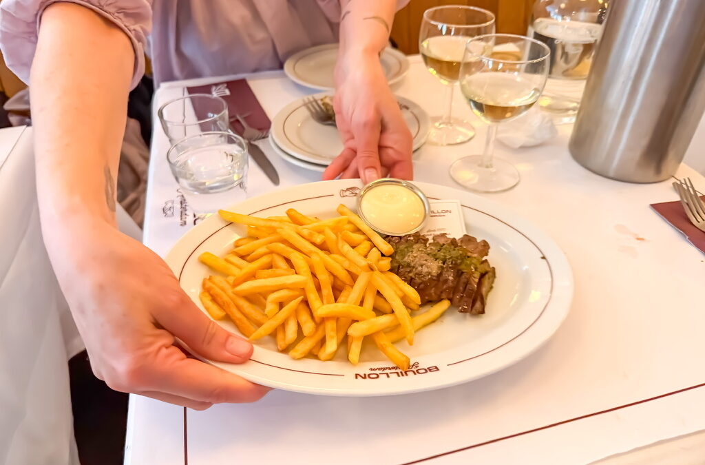 twee handen die een bord met steak friewt op tefel zetten