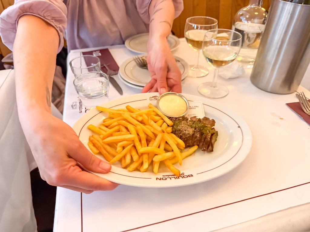 twee handen die een bord met steak friewt op tefel zetten
