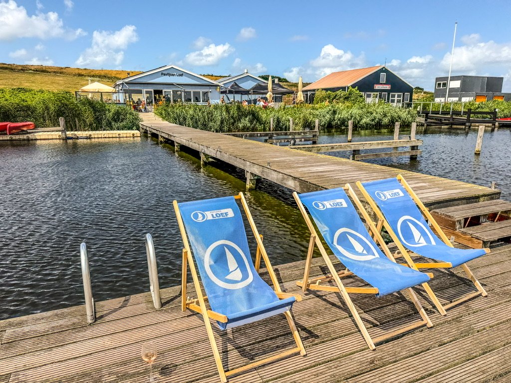 vlonder in een meer leid naar een blauw restaurant tussen het riet
